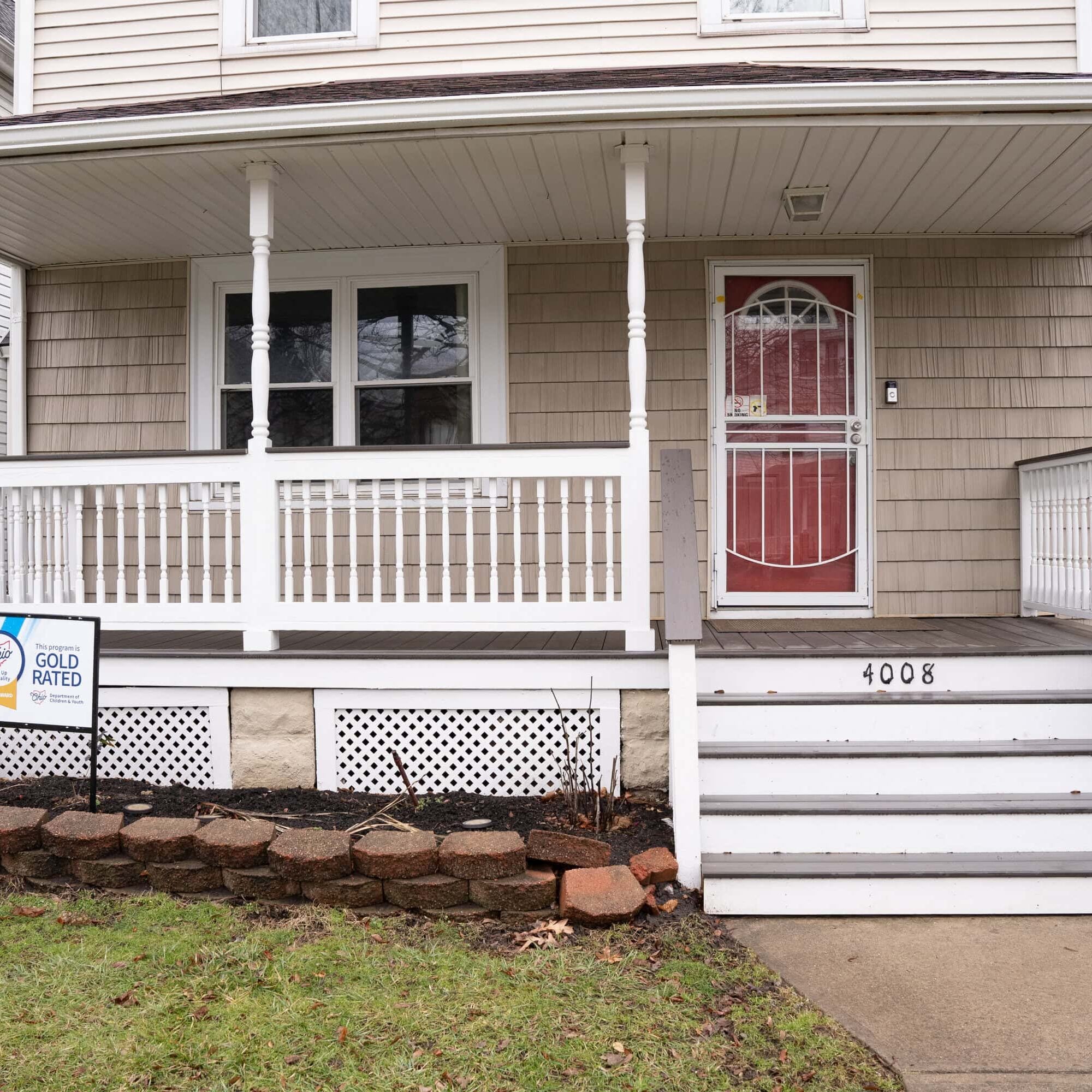 A beige house with a covered front porch, white railings, steps, and a Gold Rated Energy Star sign in the yard near house number 4008.