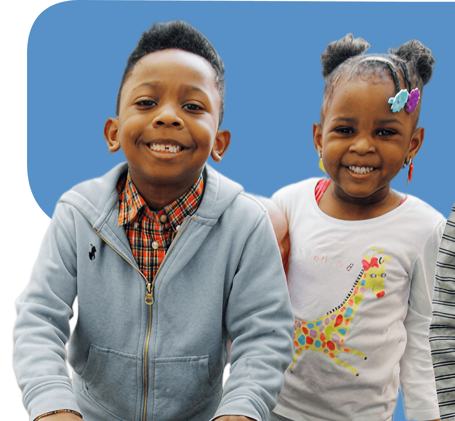 home-hero-image Two smiling children, a boy in a gray hoodie and plaid shirt and a girl in a white shirt with a giraffe design, stand side by side against a blue background.